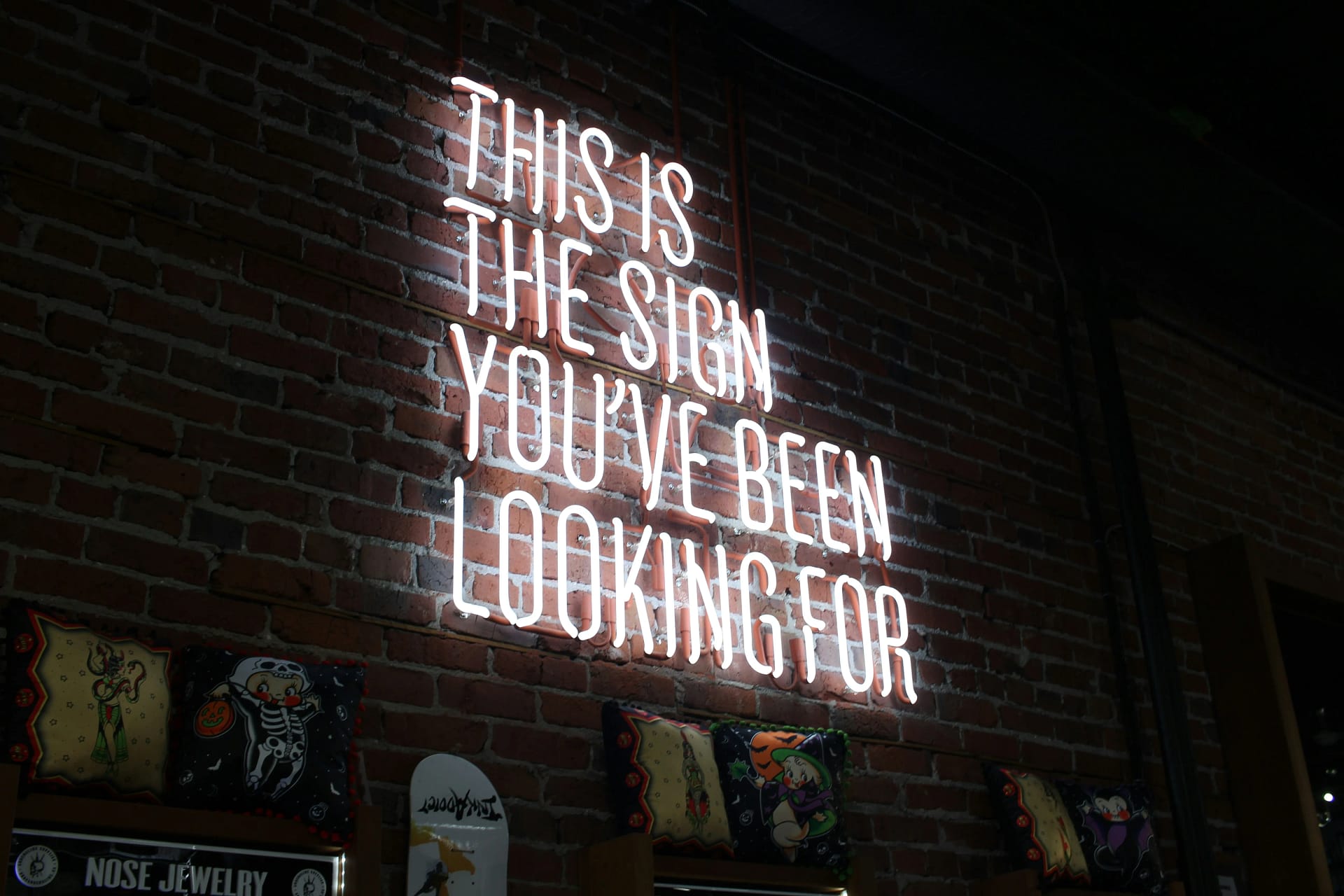 White neon sign reading "This is the sign you've been looking for" mounted on a brick wall