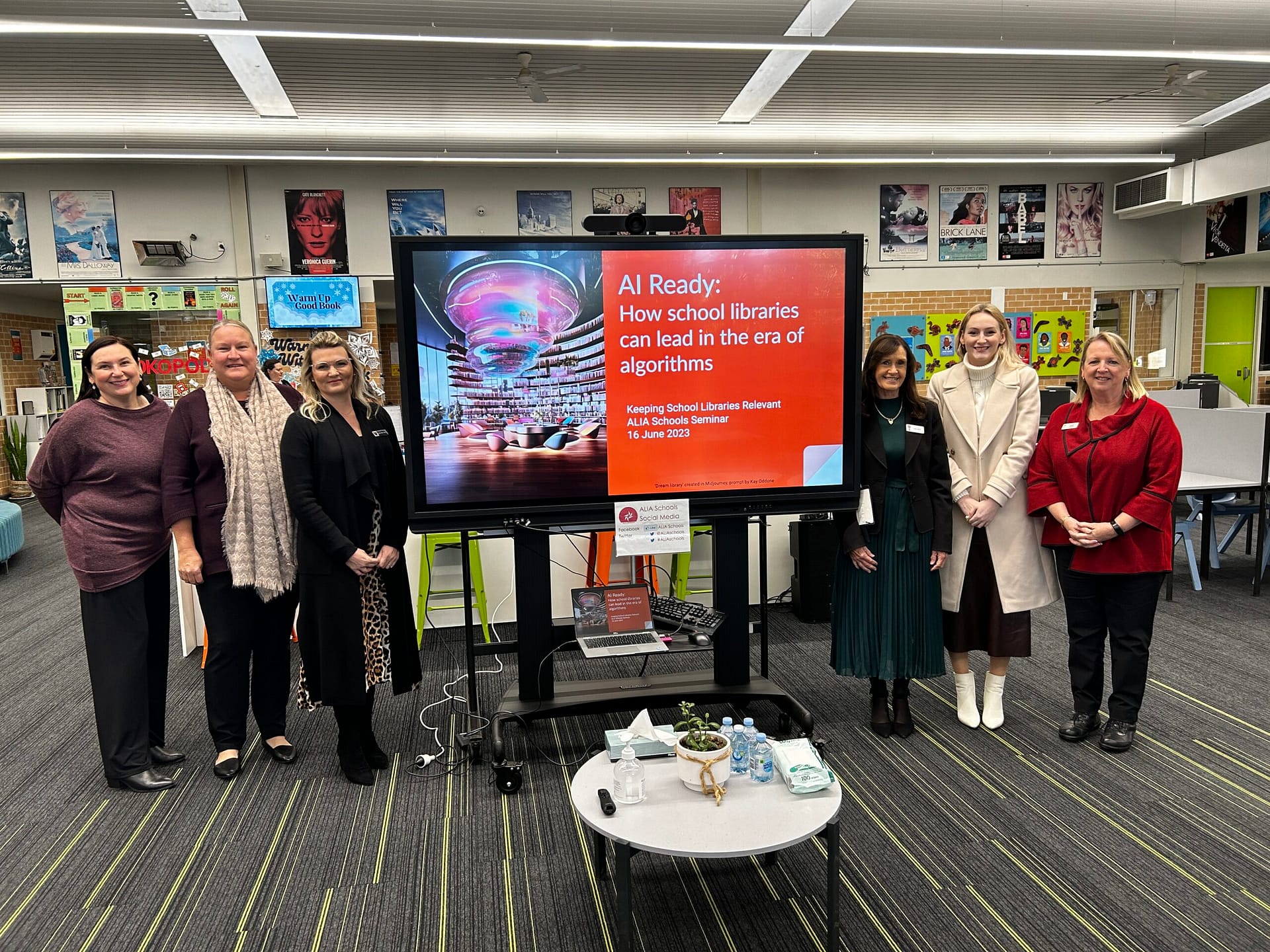 Presenters and staff standing in front of screen with keynote title slide.